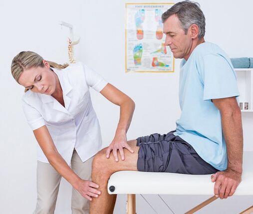 Lékař provádí vizuální vyšetření a palpaci pacienta s bolestí kolene
